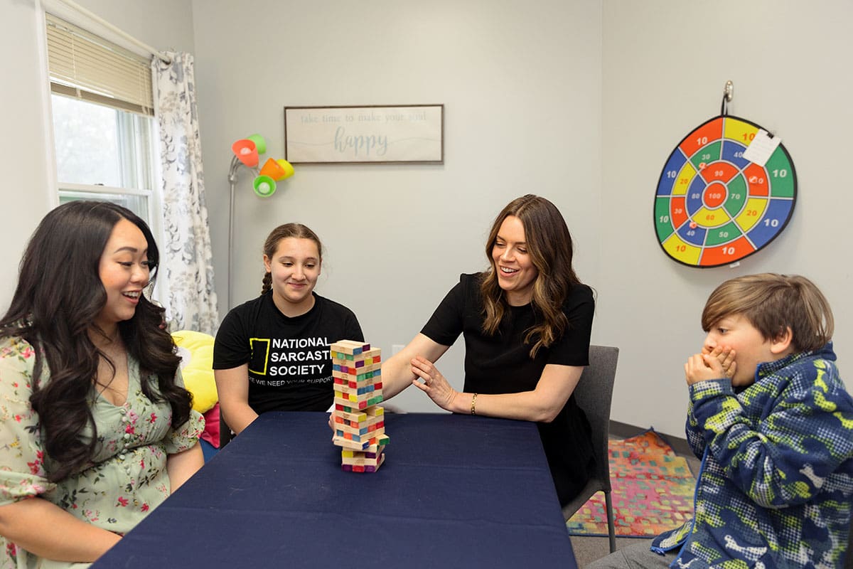 Therapists. with children sitting and playing jenga in the consult room