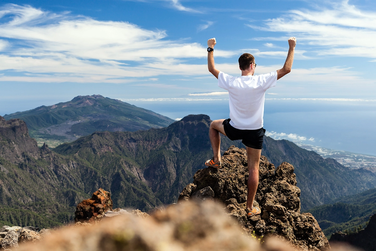 Trail runner man celebrating his success after hiking up the mountains
