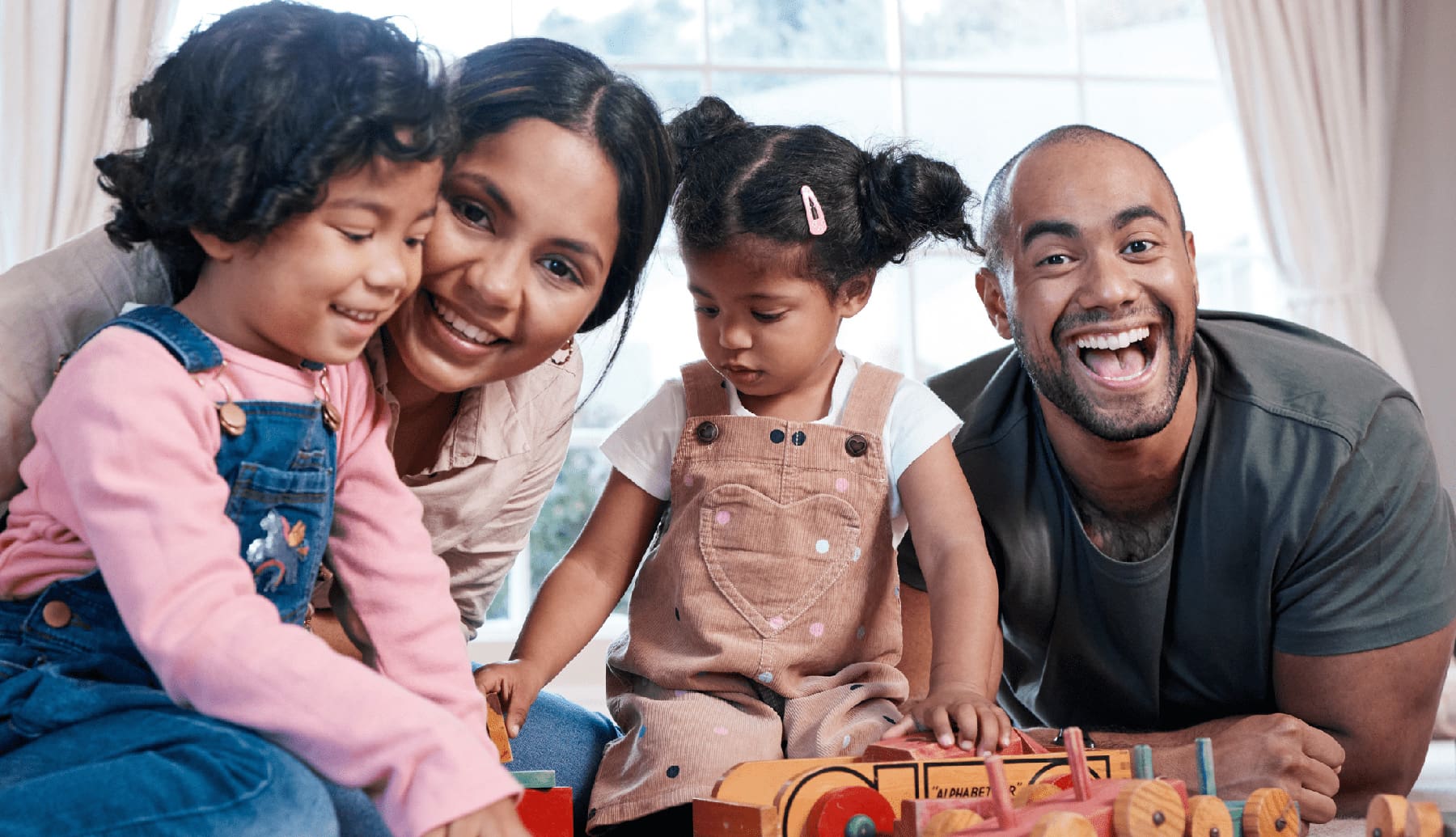 Portrait of a happy family playing together with wooden toys at home