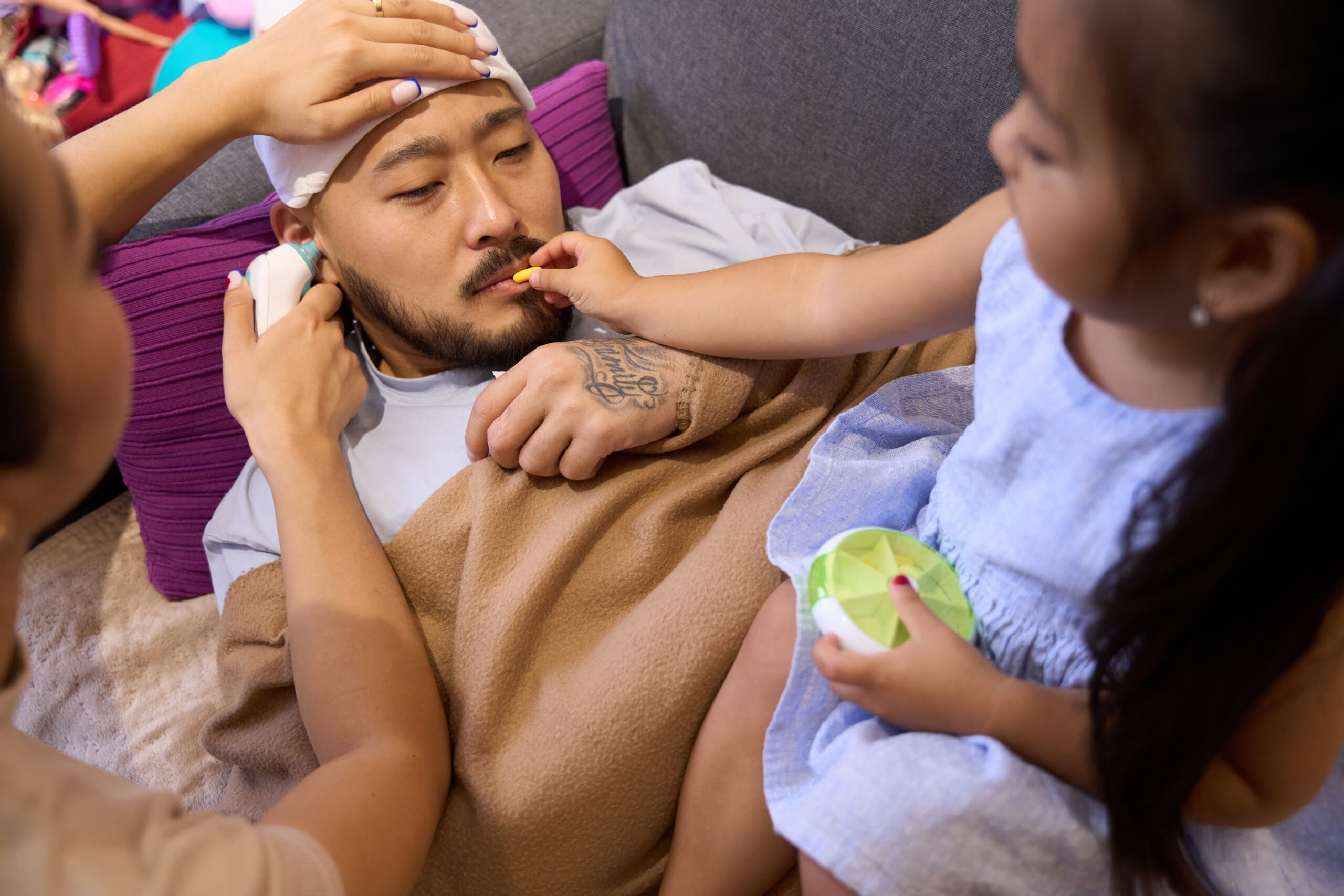 Sick asian man lying on sofa with compress on his head A sick father is cared for by his two children. They make sure he is mentally and physically healthy. This helps him take part in family activities.