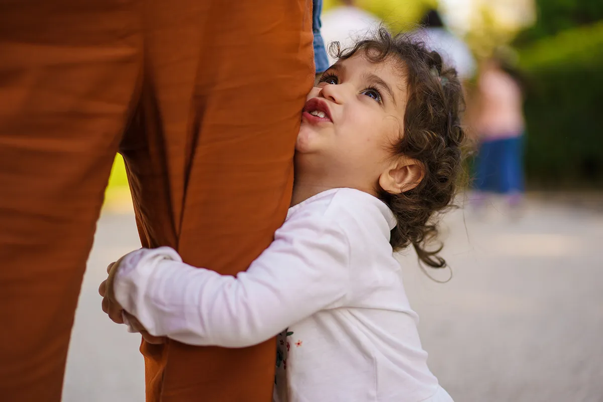 Young girl holding her mother’s leg Young Mixed-Ethnicity Girl Embracing Mother's Leg