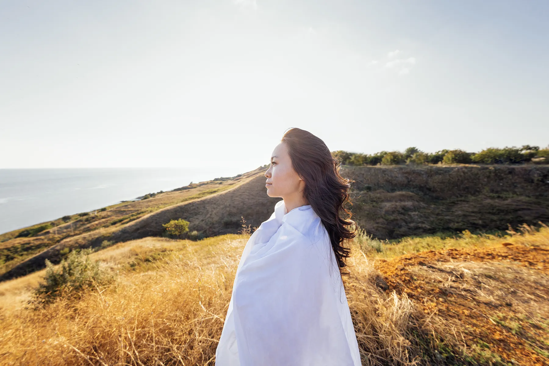 a young handsome asian woman wrapped in a white sheet on a field