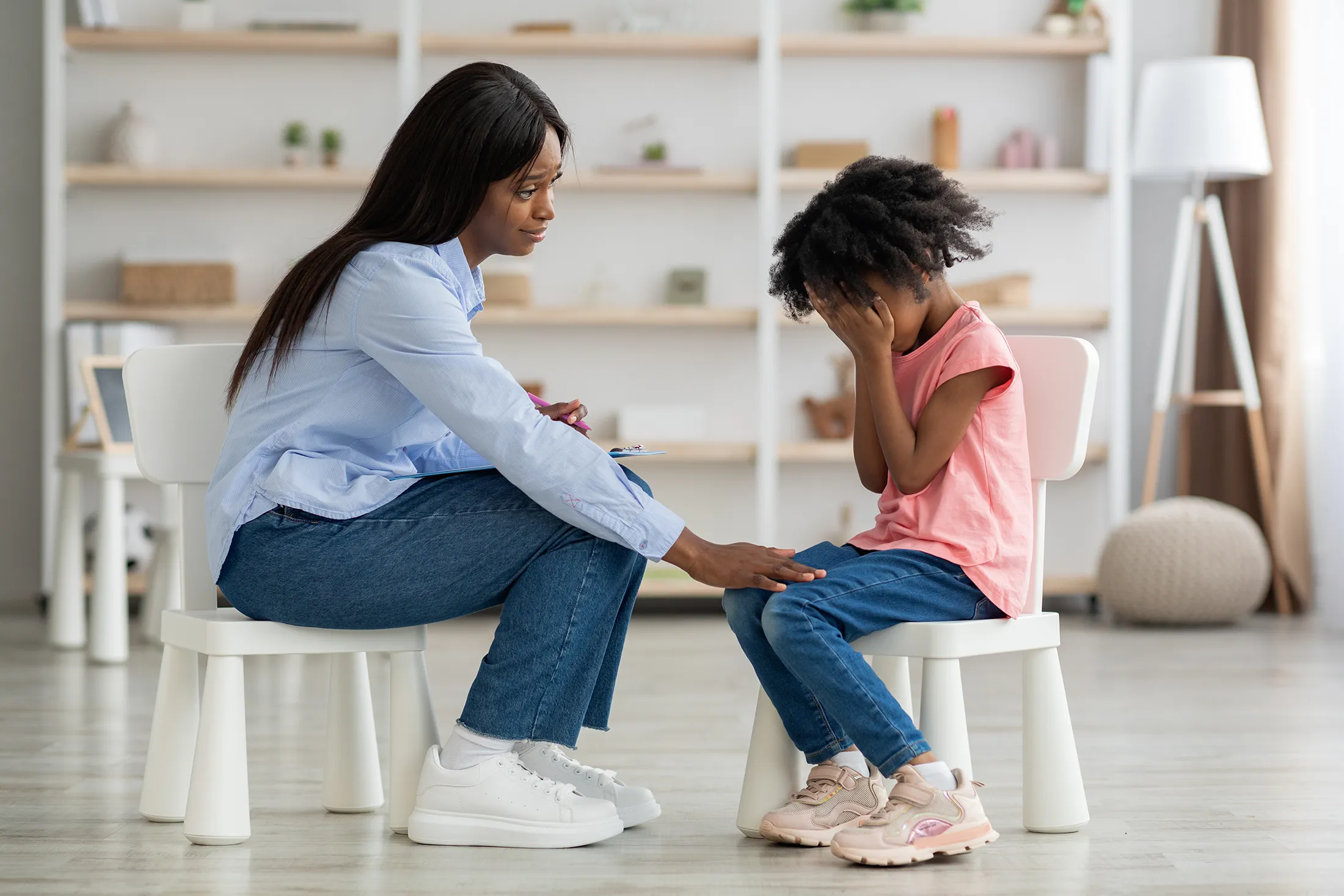 distressed-black-kid-crying-at-psychotherapy-sessi-2025-03-18-18-23-54-utc Therapist comforting a young girl during a grief counseling session.