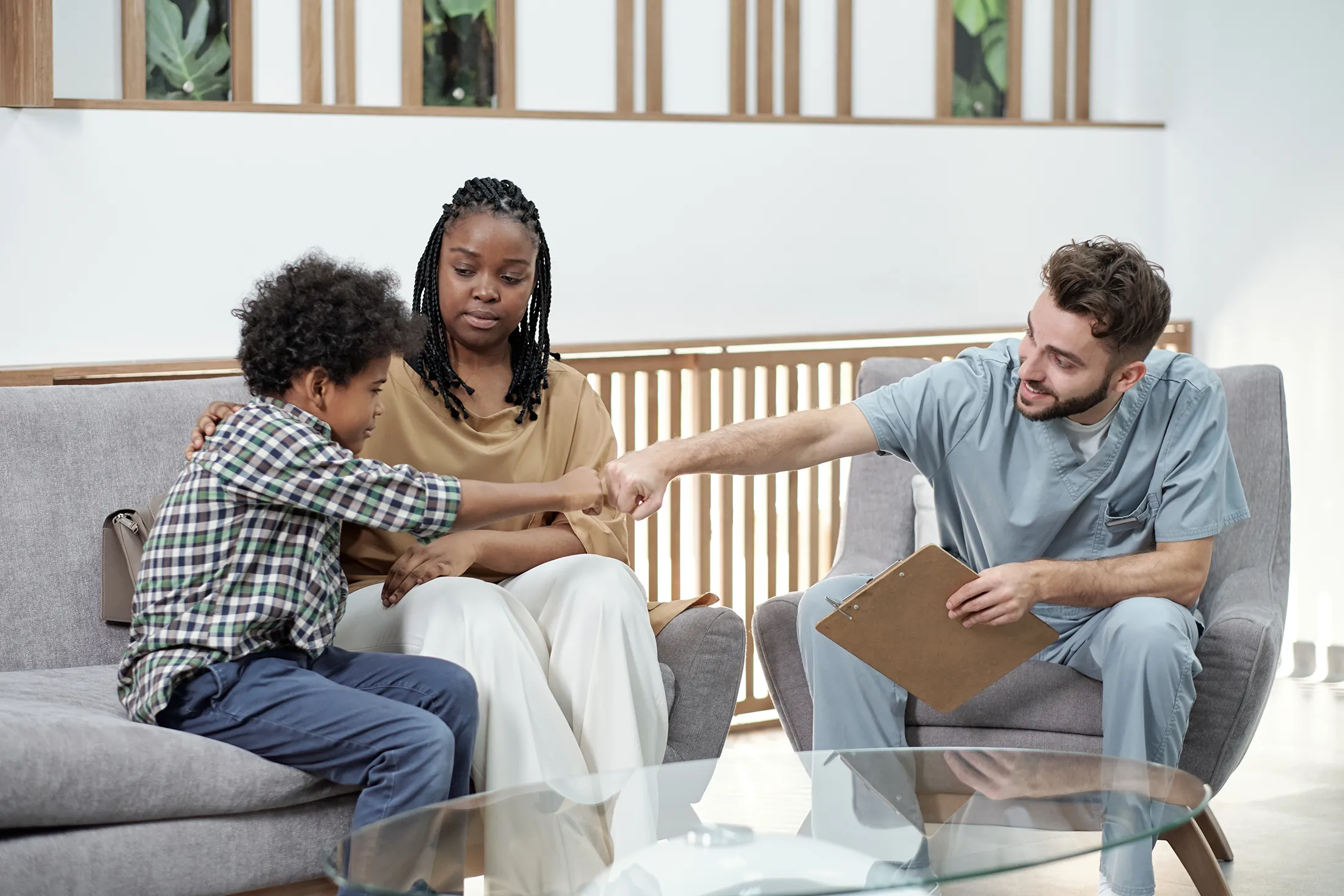 Therapist greeting a child with a fist bump during a family therapy session, showing trust-building and support for mental health treatment in New Jersey.